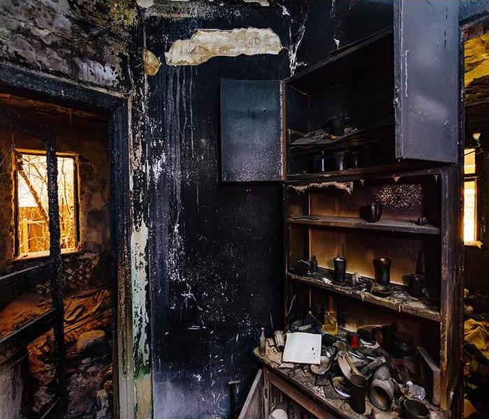 Burned kitchen cabinet, charred walls and ceiling in black soot